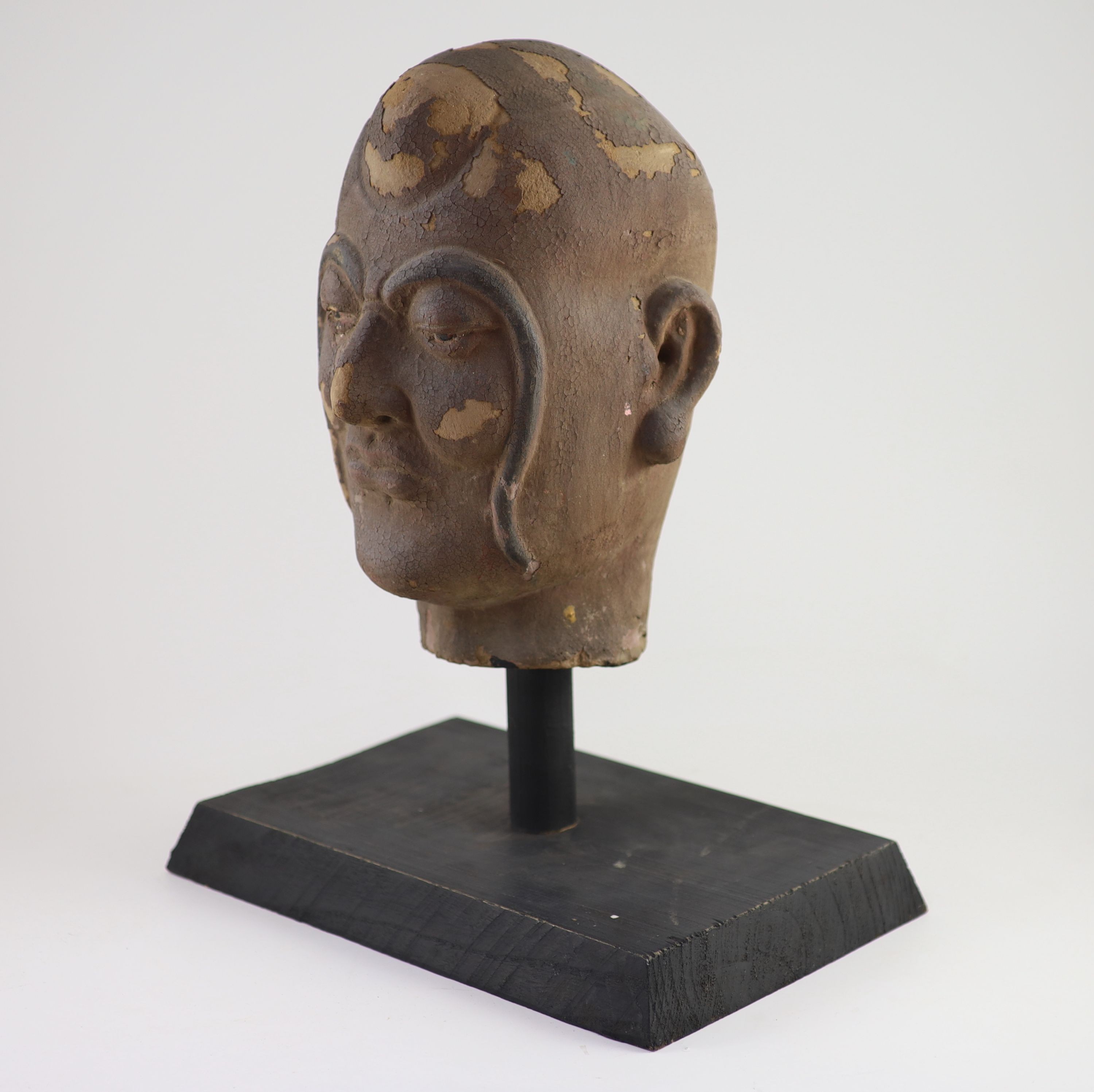 A Chinese stucco head of a luohan, Yuan-Ming dynasty, 32 cm high excluding later stand